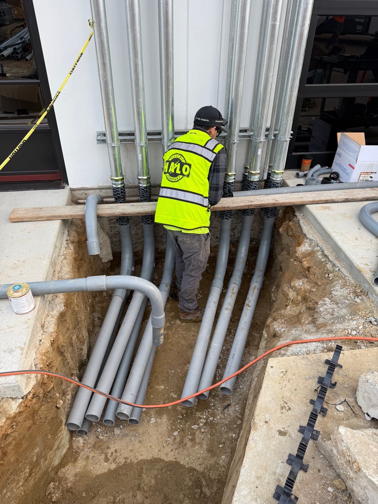 Halo Electric team member installing underground conduits connected to risers along the building