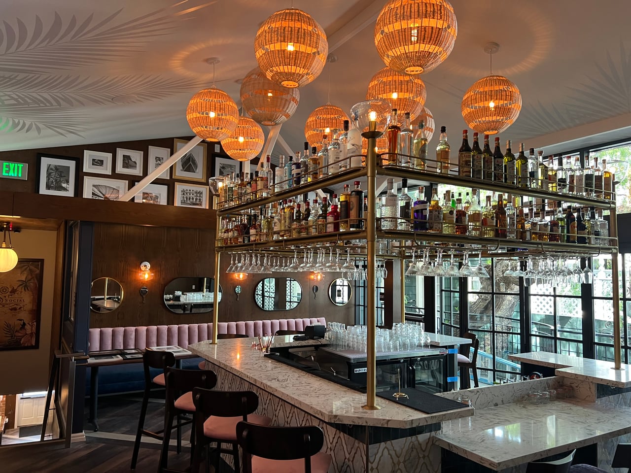 Warm woven pendant lights illuminate the marble bar at Rum Social in Laguna Beach