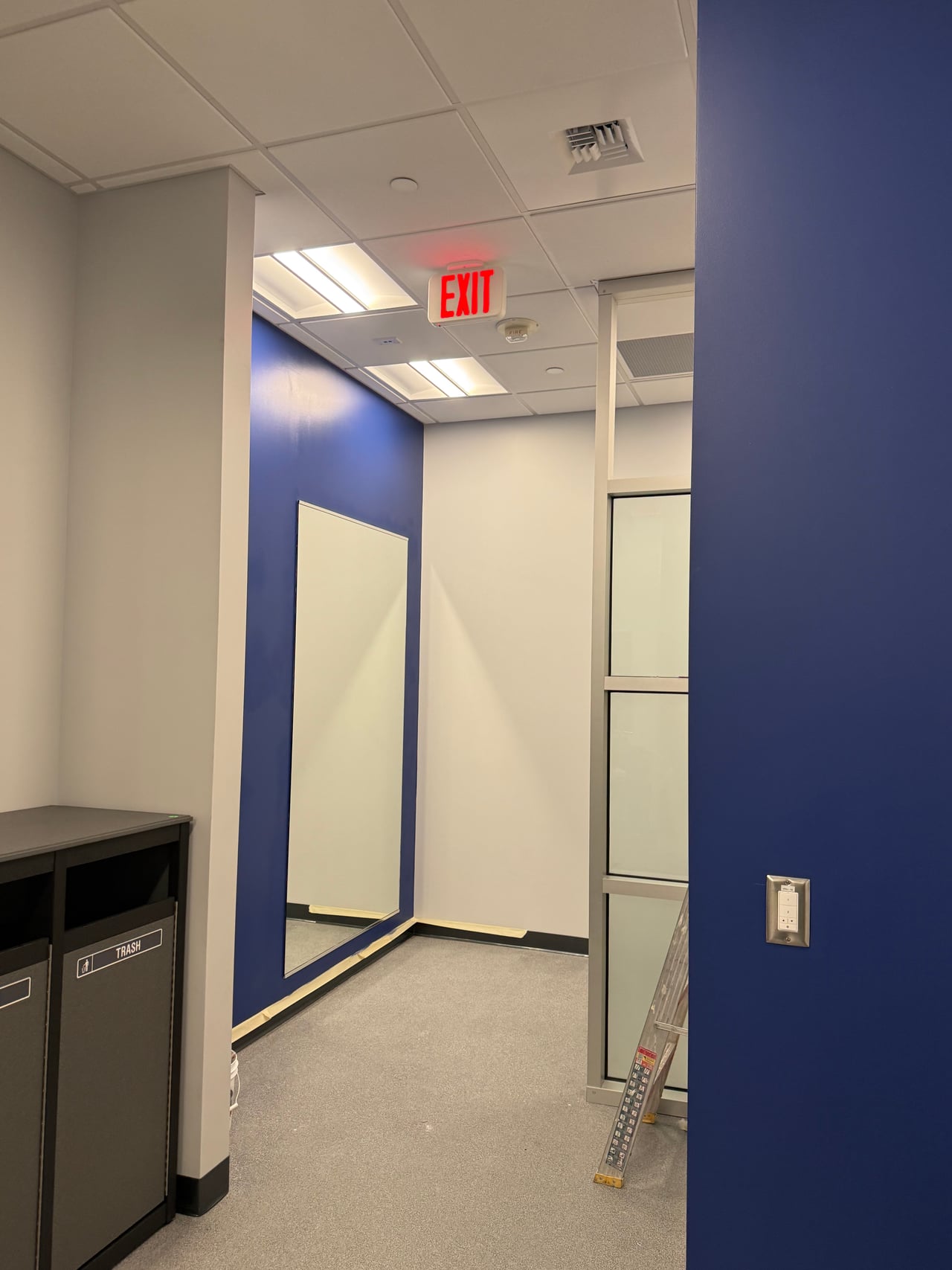 Wall-mounted lighting control on a blue wall with ceiling lights and mirrors in the locker room