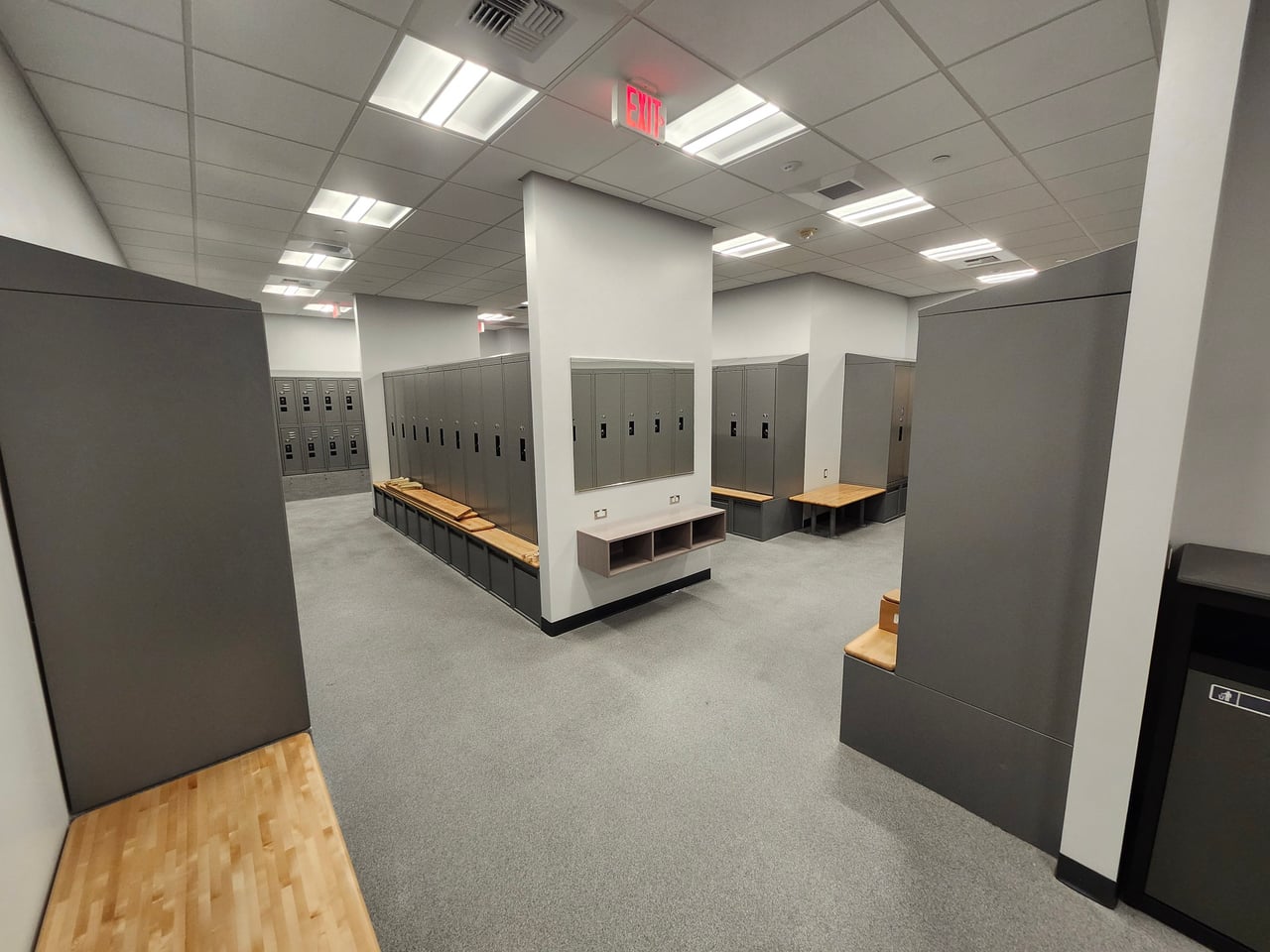 Ceiling lighting above rows of gray lockers and benches in the Huntington Beach Police Department locker room