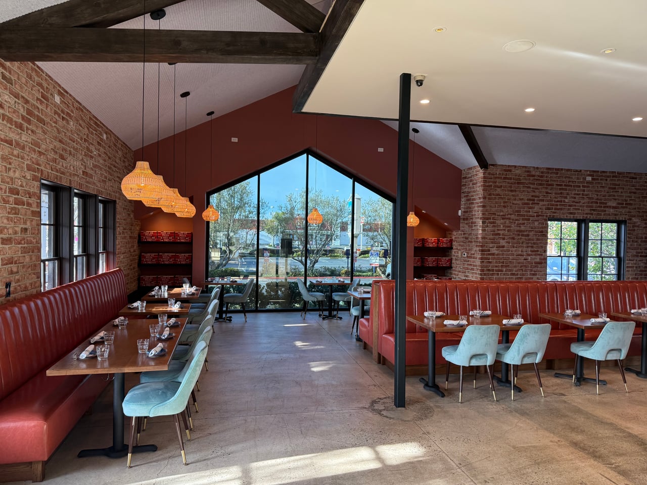 Woven pendant lights above red banquettes and dining tables at OSPI in Costa Mesa