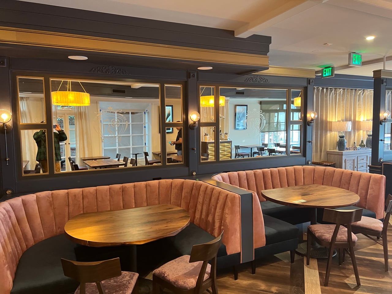 Upholstered booths, mirrors and warm wall lighting in Rum Social’s dining room