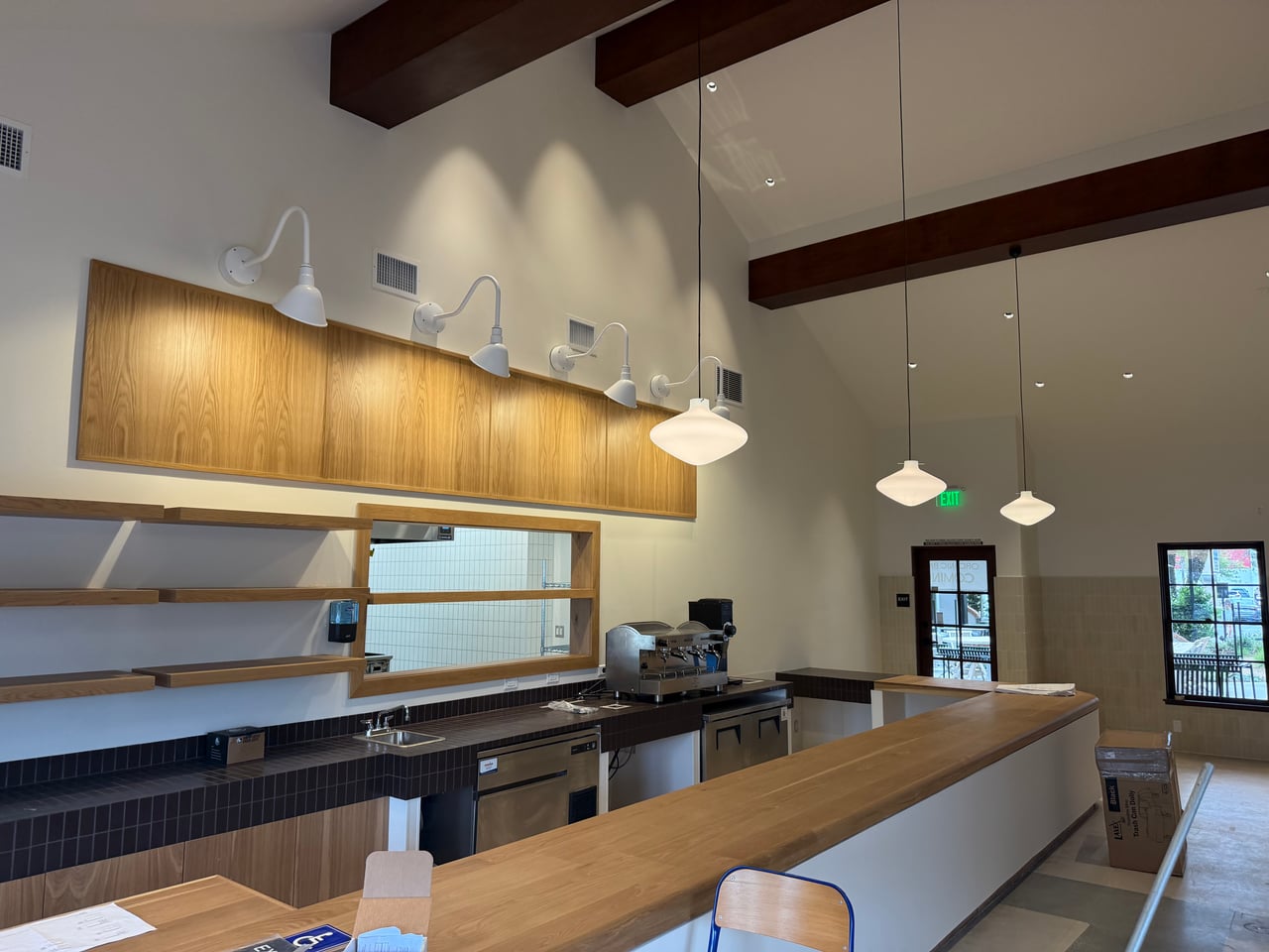 White pendant and wall lights illuminate the wood counter at Rye Goods